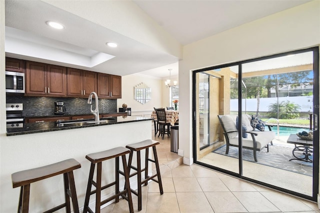 kitchen featuring pendant lighting, sink, decorative backsplash, appliances with stainless steel finishes, and light tile patterned floors