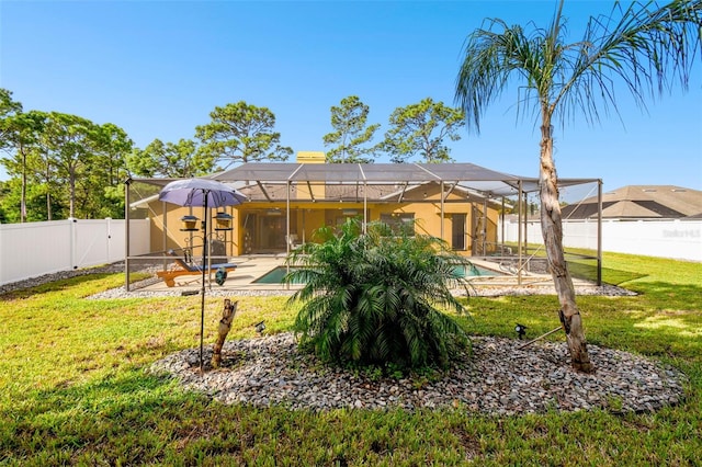 rear view of property featuring glass enclosure, a yard, a patio, and a fenced in pool