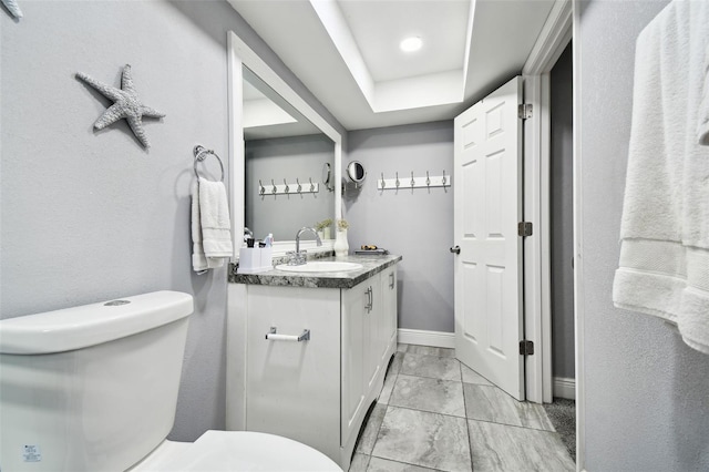 bathroom featuring vanity, a raised ceiling, and toilet