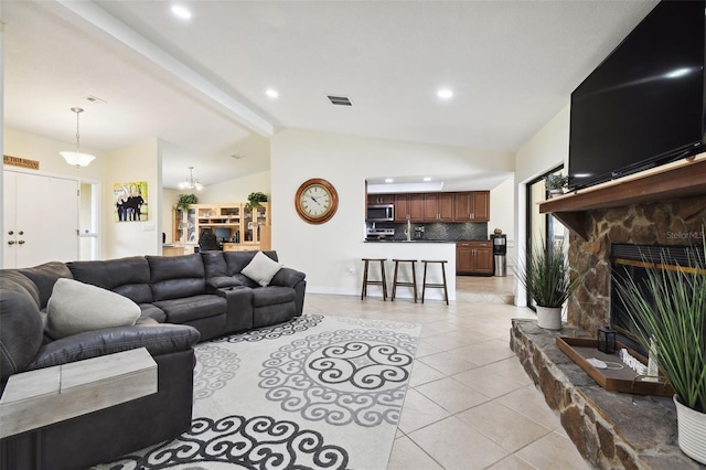 tiled living room featuring vaulted ceiling with beams, a fireplace, sink, and a notable chandelier