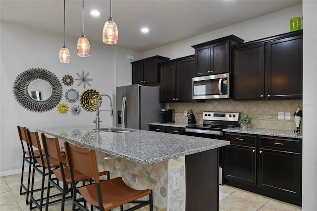 kitchen with stainless steel appliances, sink, a breakfast bar area, a center island with sink, and decorative light fixtures