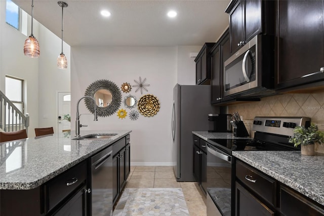 kitchen with stainless steel appliances, tasteful backsplash, sink, hanging light fixtures, and a center island with sink