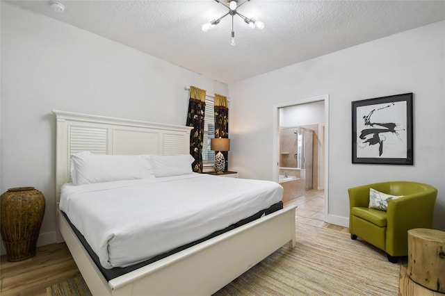 bedroom with a notable chandelier, a textured ceiling, light hardwood / wood-style floors, and ensuite bathroom