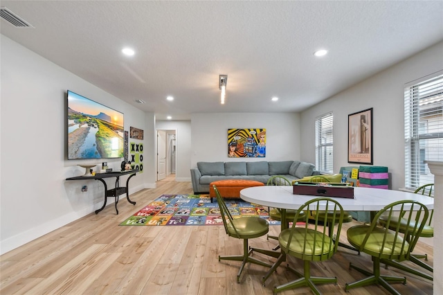 dining area with a textured ceiling, light hardwood / wood-style flooring, and a healthy amount of sunlight