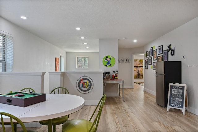 dining area with a textured ceiling and light hardwood / wood-style floors