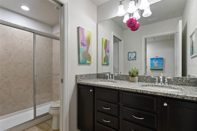 bathroom featuring tile patterned floors, vanity, toilet, and a shower with shower door