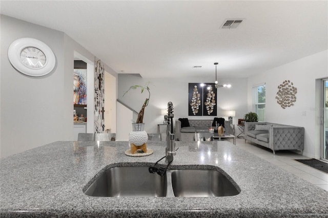 kitchen featuring light tile patterned flooring, sink, an inviting chandelier, decorative light fixtures, and stone counters