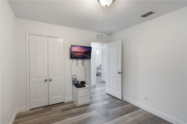 unfurnished bedroom with a closet, a textured ceiling, and light hardwood / wood-style flooring