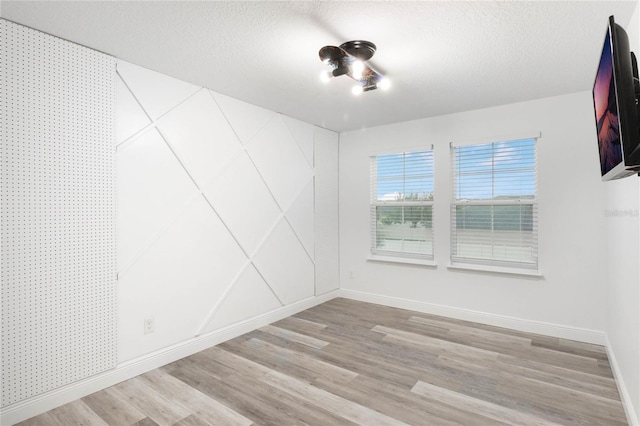 empty room with a textured ceiling and light hardwood / wood-style floors