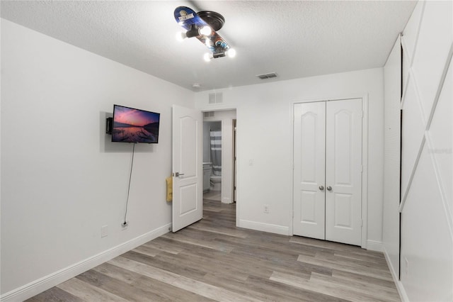 unfurnished bedroom with a textured ceiling, a closet, and light wood-type flooring