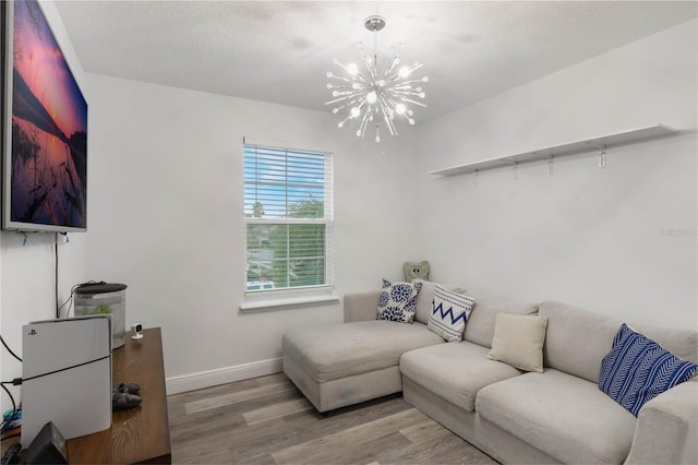 living room with light hardwood / wood-style floors, a textured ceiling, and an inviting chandelier