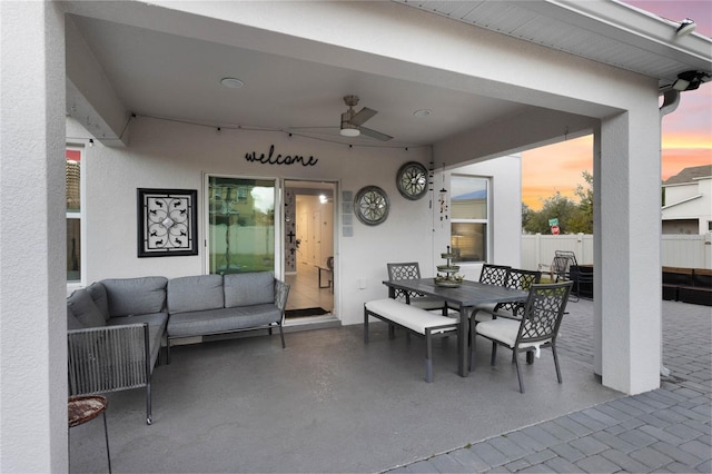 patio terrace at dusk with outdoor lounge area and ceiling fan