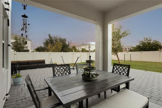 patio terrace at dusk featuring a lawn