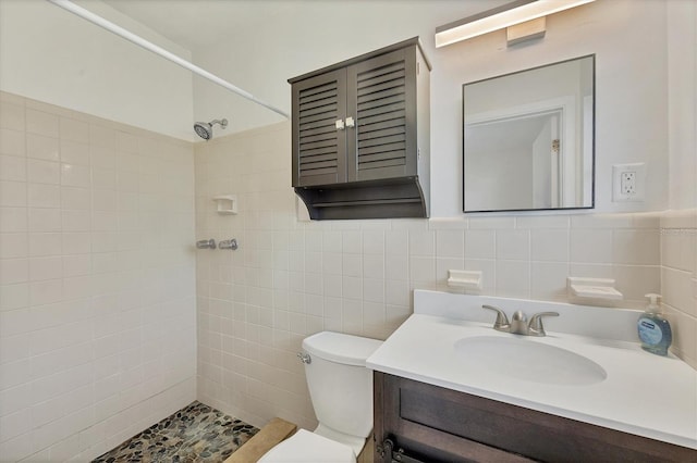 bathroom with a tile shower, tile walls, vanity, and toilet