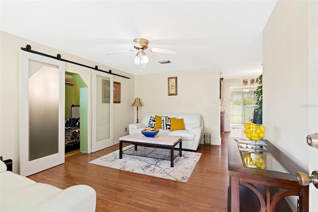 living room with a barn door, hardwood / wood-style floors, and ceiling fan