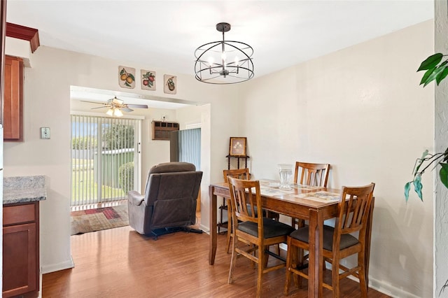 dining room with ceiling fan with notable chandelier and hardwood / wood-style floors