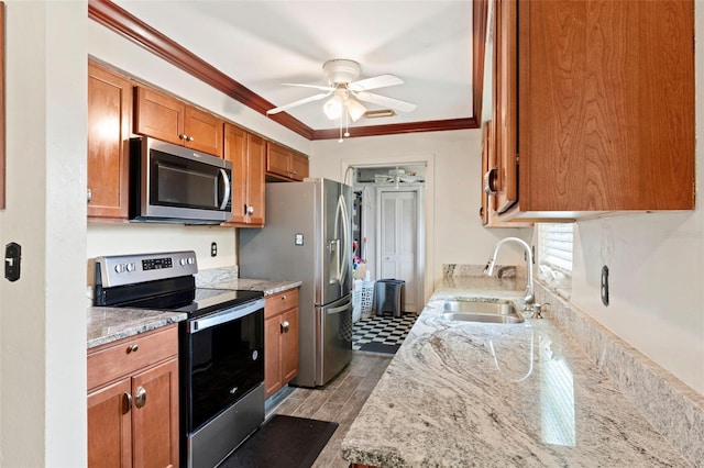 kitchen with appliances with stainless steel finishes, light hardwood / wood-style floors, light stone counters, ornamental molding, and sink