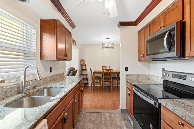 kitchen with appliances with stainless steel finishes, ornamental molding, light wood-type flooring, and sink