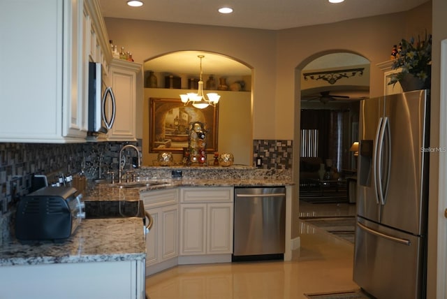 kitchen featuring light stone counters, sink, hanging light fixtures, backsplash, and appliances with stainless steel finishes