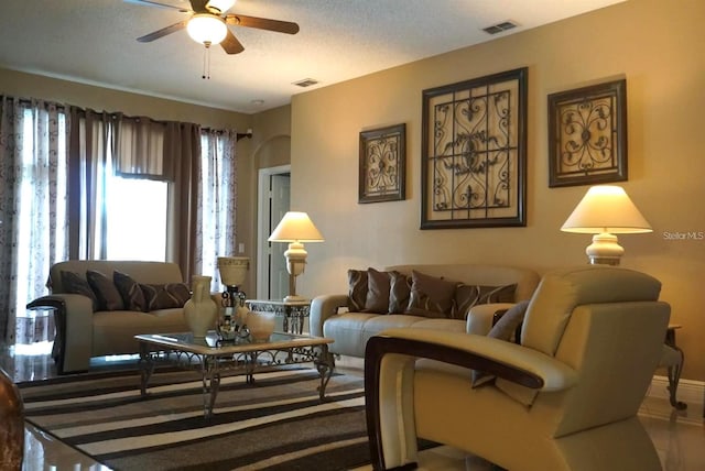 living room featuring ceiling fan and a textured ceiling