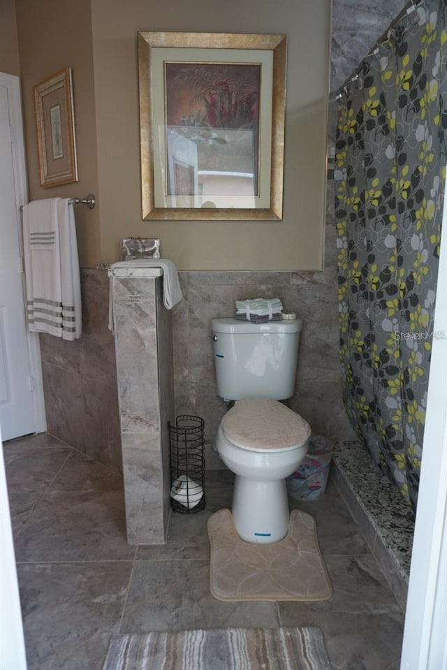 bathroom featuring tile walls, walk in shower, and toilet