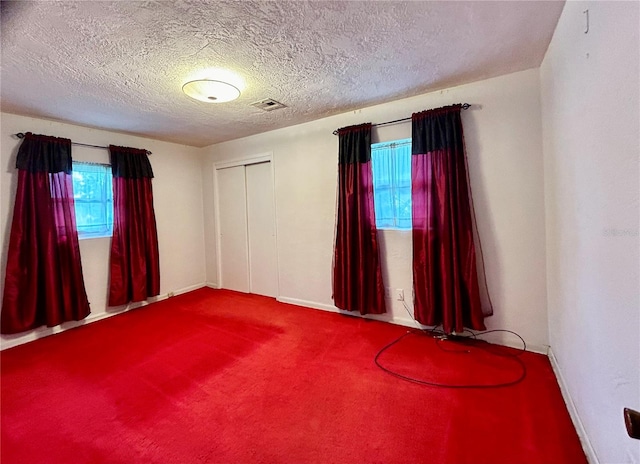 unfurnished room with a textured ceiling and carpet flooring