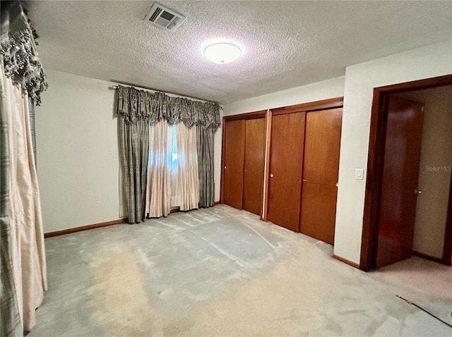 unfurnished bedroom with a textured ceiling and light carpet