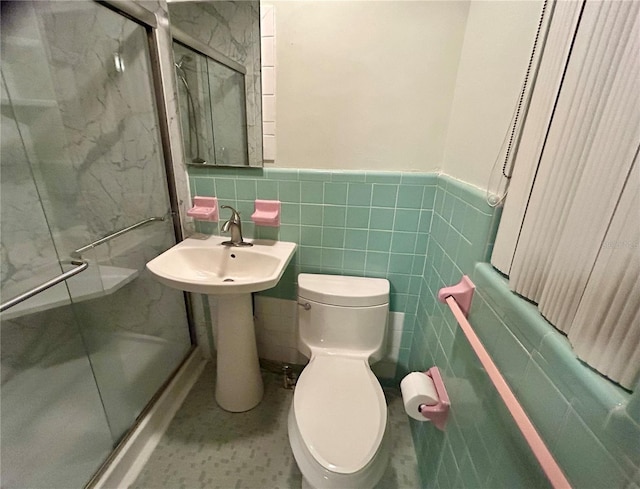 bathroom featuring tile walls, toilet, and a shower with door