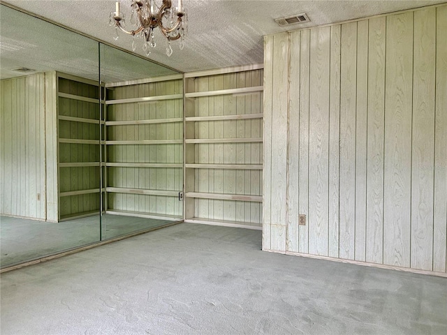 interior space with a textured ceiling, wood walls, and a chandelier