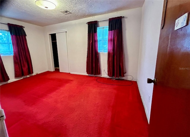 carpeted empty room with a textured ceiling