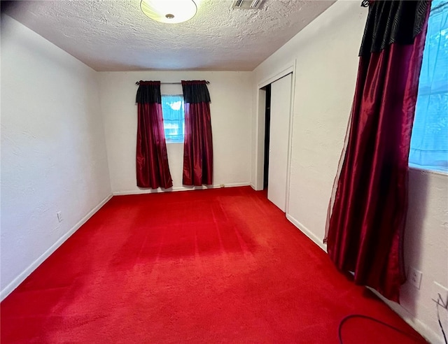 unfurnished room featuring a textured ceiling and carpet floors