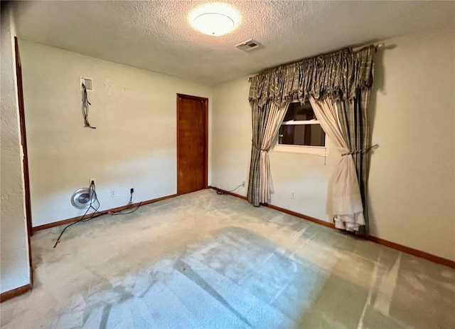 carpeted empty room featuring a textured ceiling