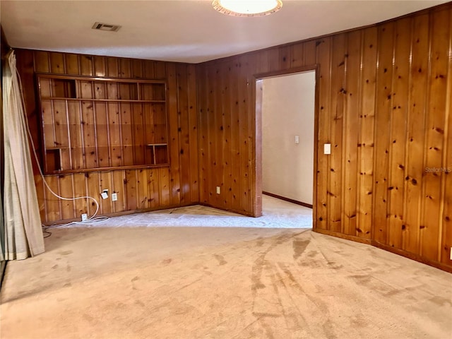 spare room featuring wooden walls and light colored carpet