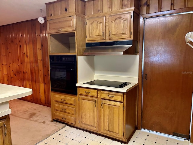 kitchen featuring black appliances and wood walls