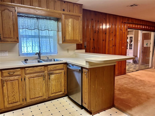 kitchen with dishwasher, wooden walls, sink, and kitchen peninsula