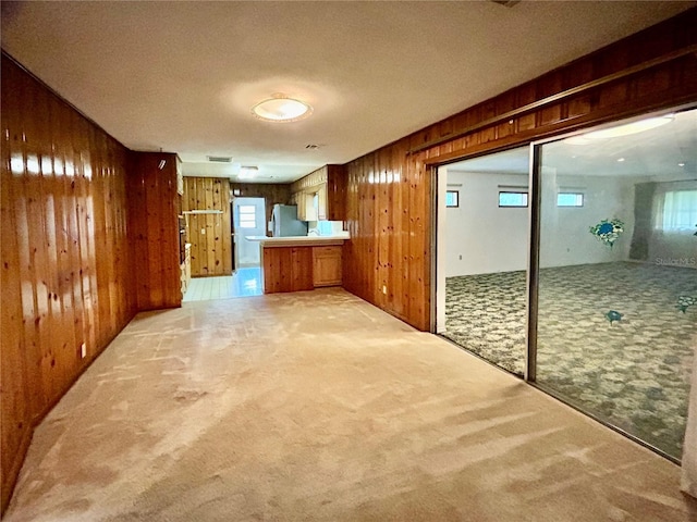 hall with wooden walls, a textured ceiling, and carpet flooring