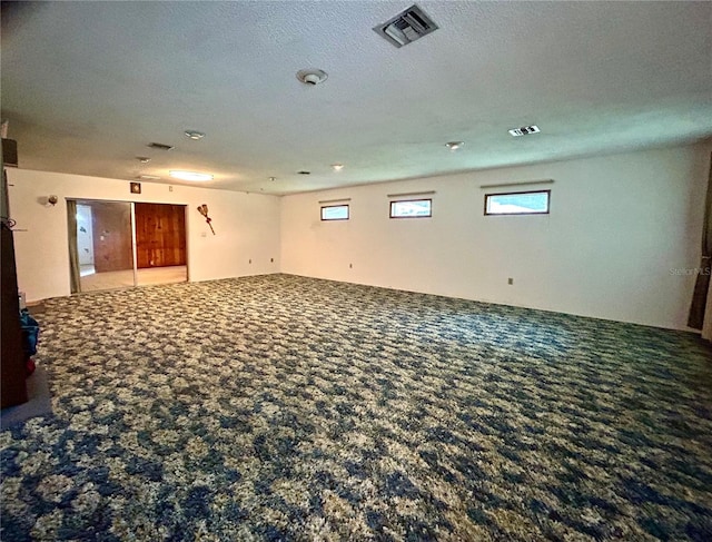 carpeted empty room featuring a textured ceiling