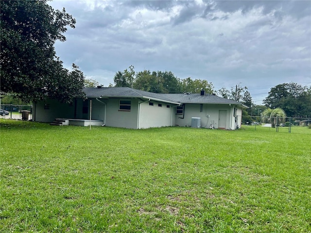 back of property with cooling unit and a yard