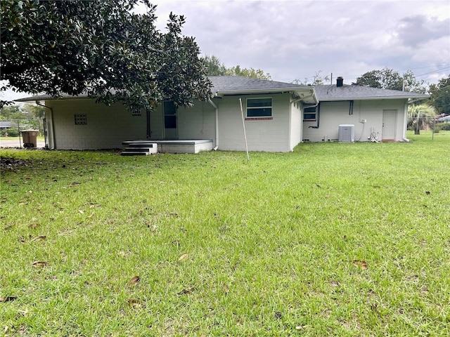 back of property with a yard and central AC