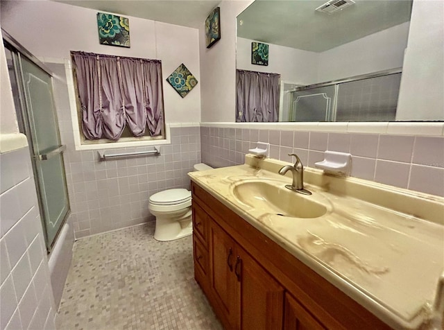 full bathroom featuring shower / bath combination with glass door, vanity, toilet, tile walls, and tile patterned flooring