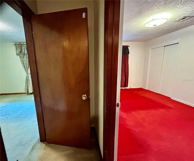 hall featuring light colored carpet and a textured ceiling