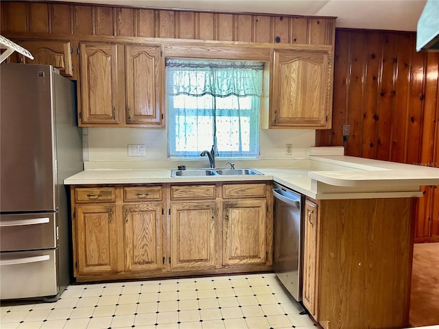 kitchen featuring stainless steel appliances, kitchen peninsula, wooden walls, and sink