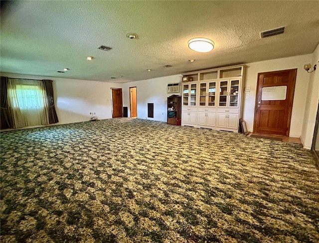 carpeted spare room with a textured ceiling and an AC wall unit