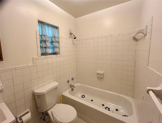 bathroom with tiled shower / bath, tile walls, and toilet