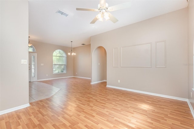 unfurnished room with ceiling fan with notable chandelier and light hardwood / wood-style floors