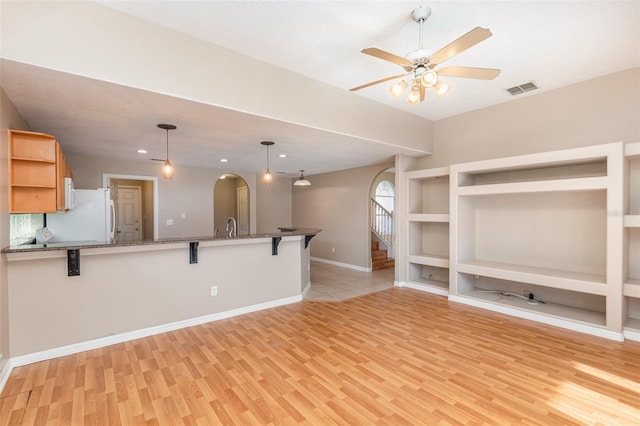 unfurnished living room featuring ceiling fan, light wood-type flooring, and sink