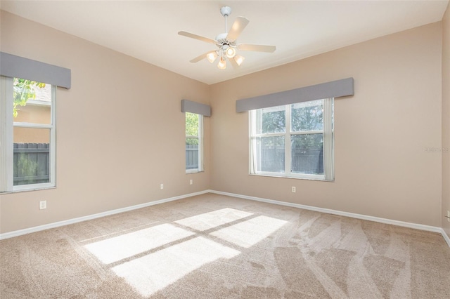 empty room with light carpet, ceiling fan, and a healthy amount of sunlight