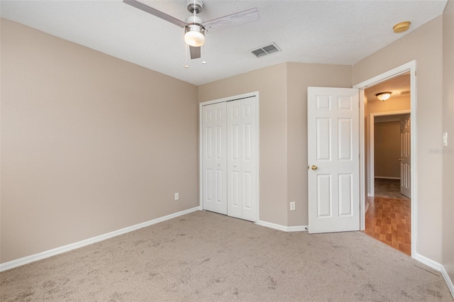 unfurnished bedroom featuring a textured ceiling, ceiling fan, light colored carpet, and a closet