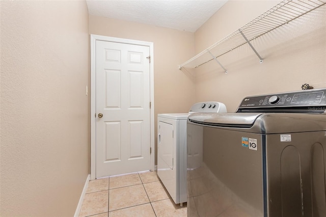 laundry room with light tile patterned flooring, a textured ceiling, and washing machine and clothes dryer