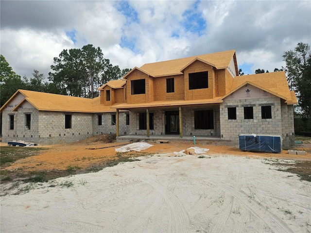 unfinished property featuring central AC, covered porch, and stone siding